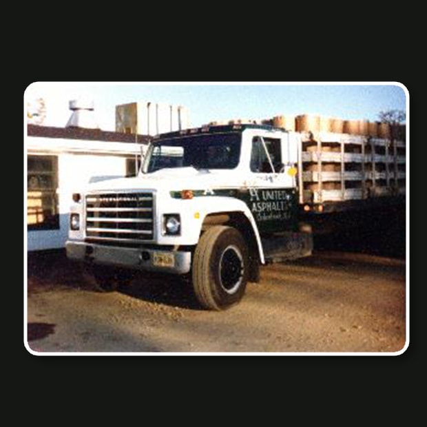 Old-Stakebody-Truck-Hauling-Packaged-Asphalt Old Stakebody Truck Hauling Packaged Asphalt